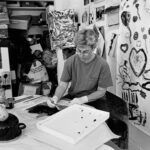 Black and white photo of white woman with short hair at River Gallery School, making art