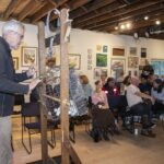 Man pulling balls from an auction basket to award paintings selected at River Gallery School's Off the Wall fundraiser
